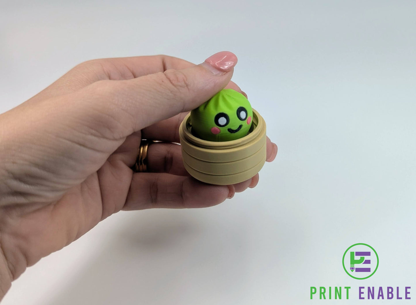 Dumpling Clicker held in hand showing compact pocket-sized fidget design and scale reference