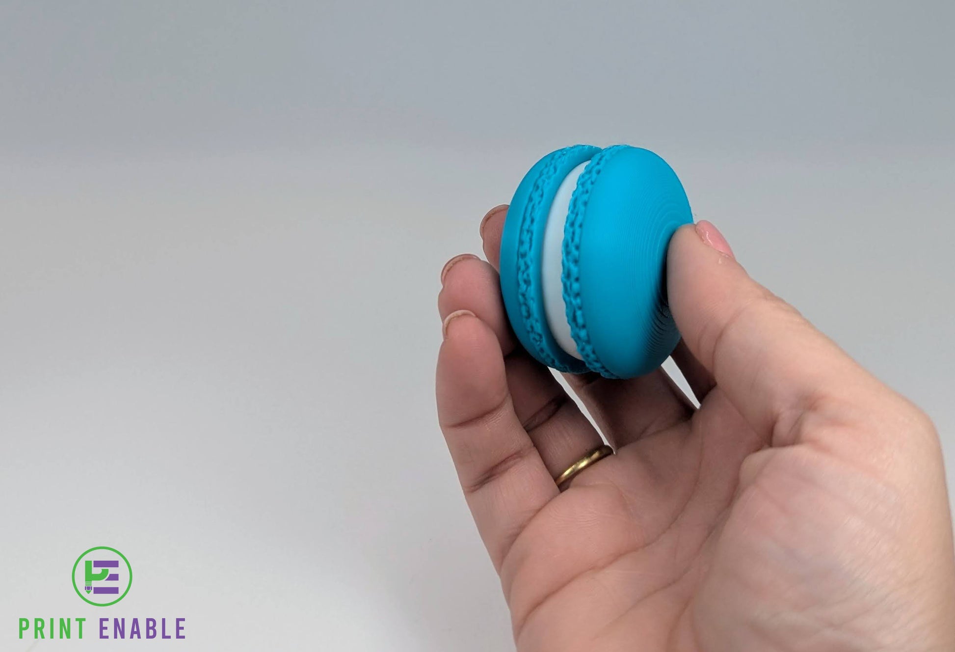 Blue macaron clicker keychain held in hand