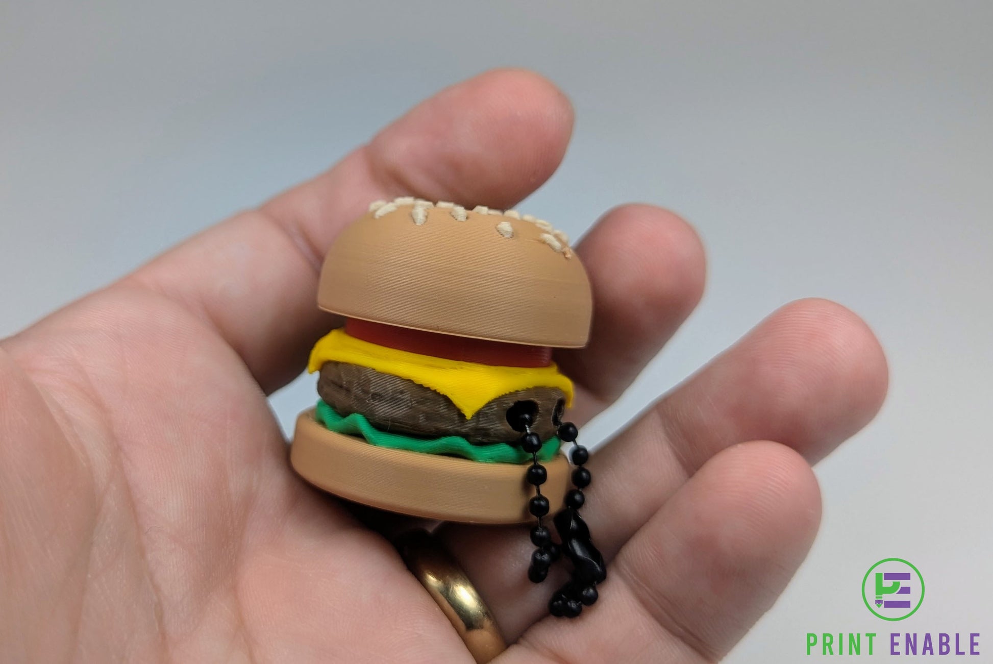 Burger Clicker shown in hand demonstrating compact pocket-sized design.